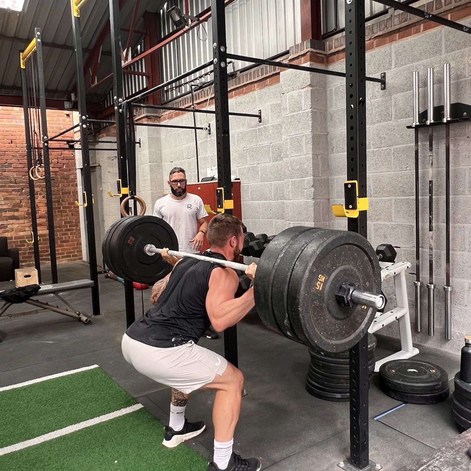 Ahsan coaching a barbell squat at Rise Above Fitness